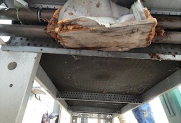 Underside view of an old, corroded HVAC coil with insulation damage.