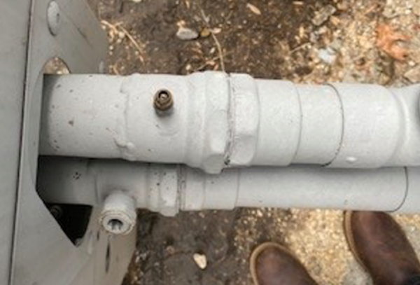Close-up of metal piping connections near an HVAC coil unit.