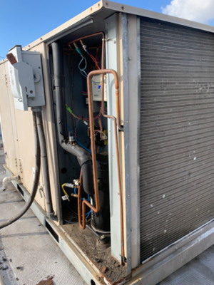 Opened rooftop HVAC unit showing internal coils, wiring, and components.